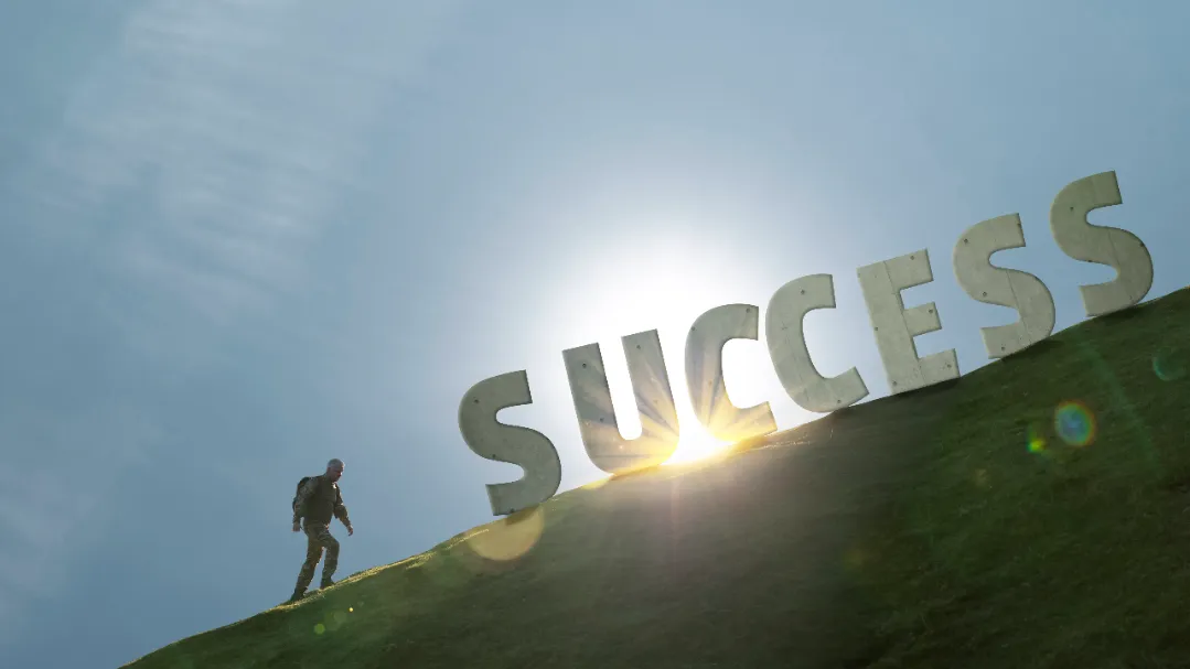 A professional climbing uphill toward giant 3D letters spelling "SUCCESS" with sunlight behind, symbolizing the journey and effort to become an outstanding recruitment agency.